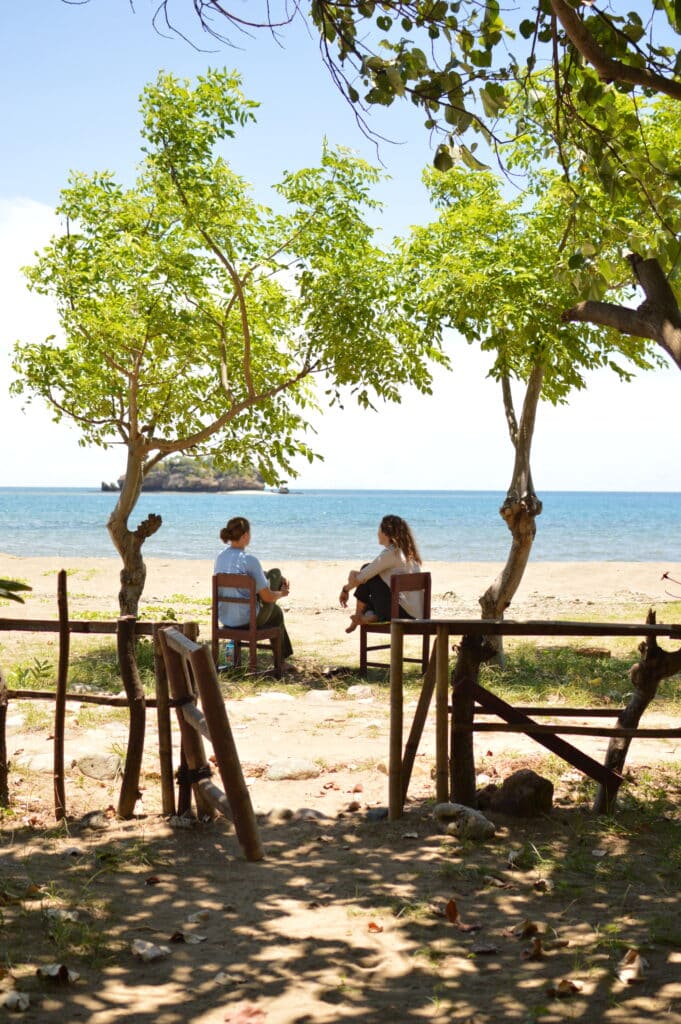 two girls sitting in chairs on beach talking and looking out