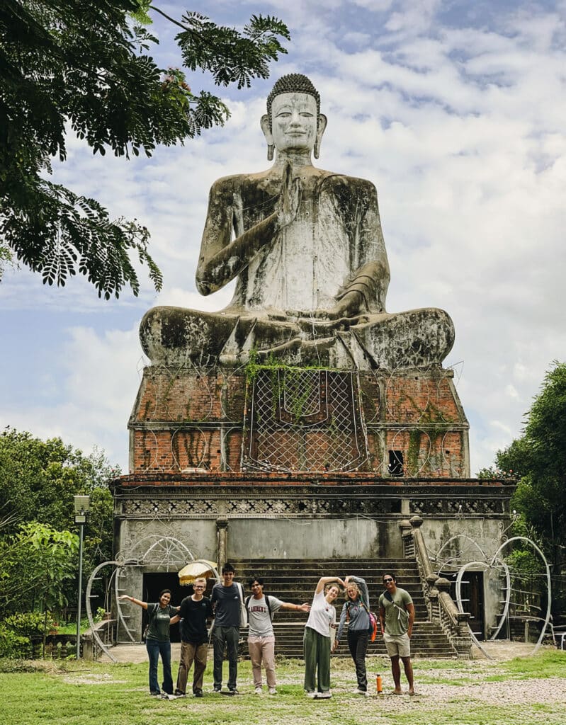 people posing in front of large statue of Buddha