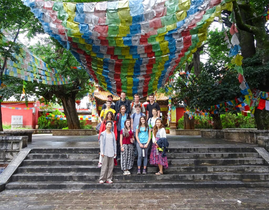 group standing on steps under prayer flags