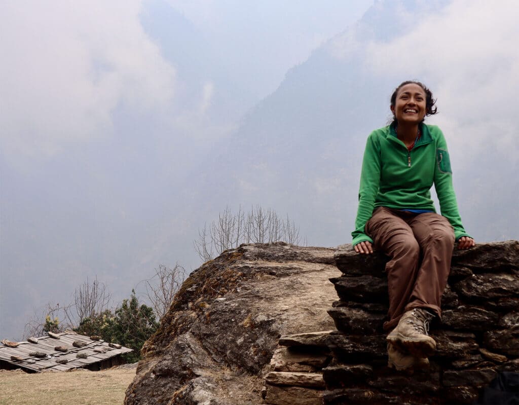 Person in green sweater sitting on rock