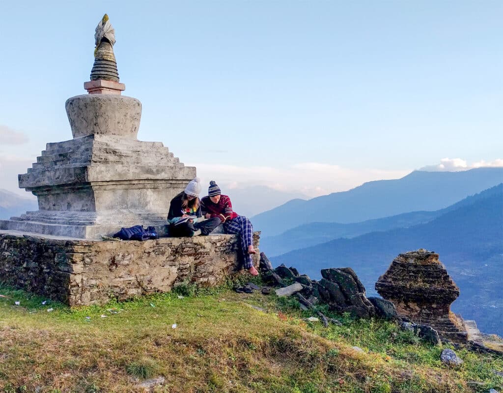 people sitting on stupa overlooking valley