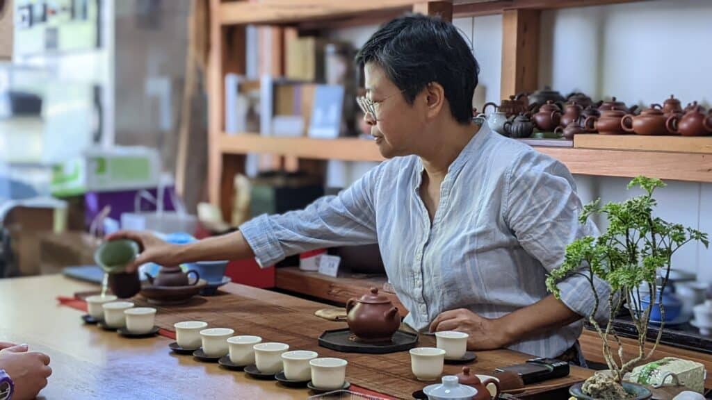 woman sitting at table pouring cups of tea