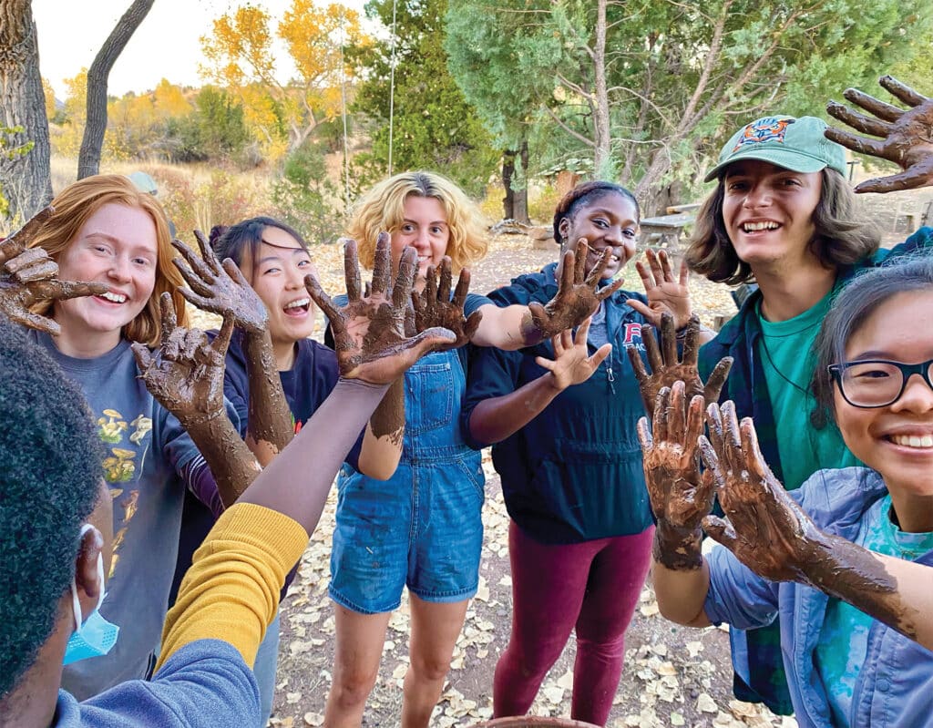 people laughing and showing their hands covered in mud